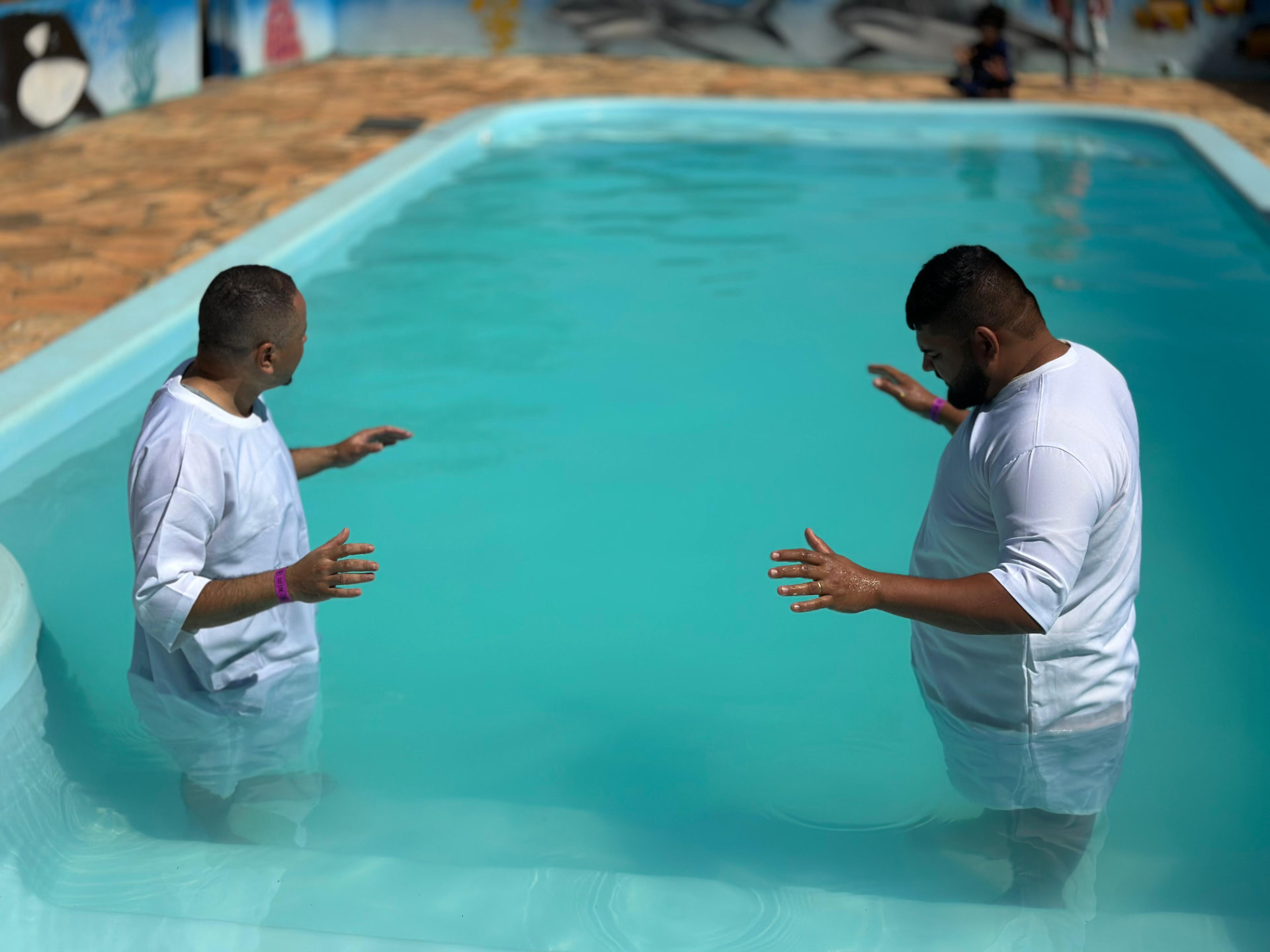 Pastores ministrando durante o batismo nas águas